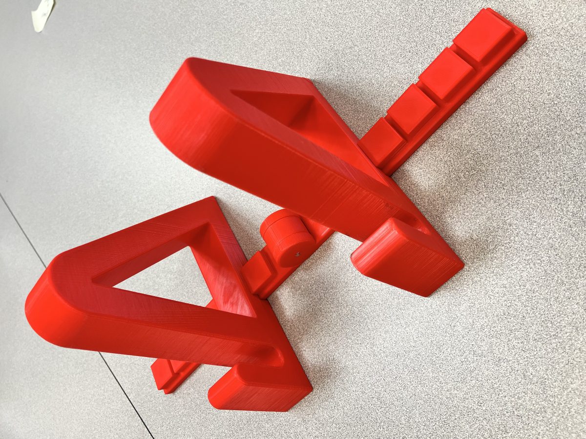 red, adjustable skateboard stand that was 3-D printed.
